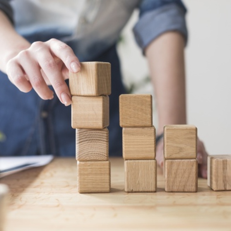 Man stacks wooden building blocks