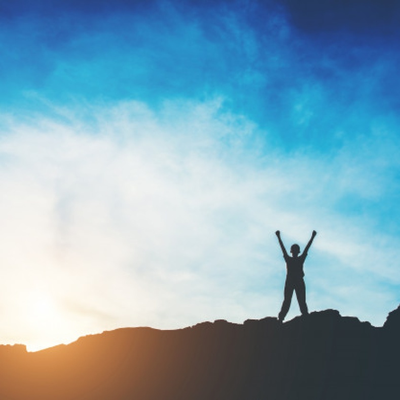 Man with raised arms on a mountain